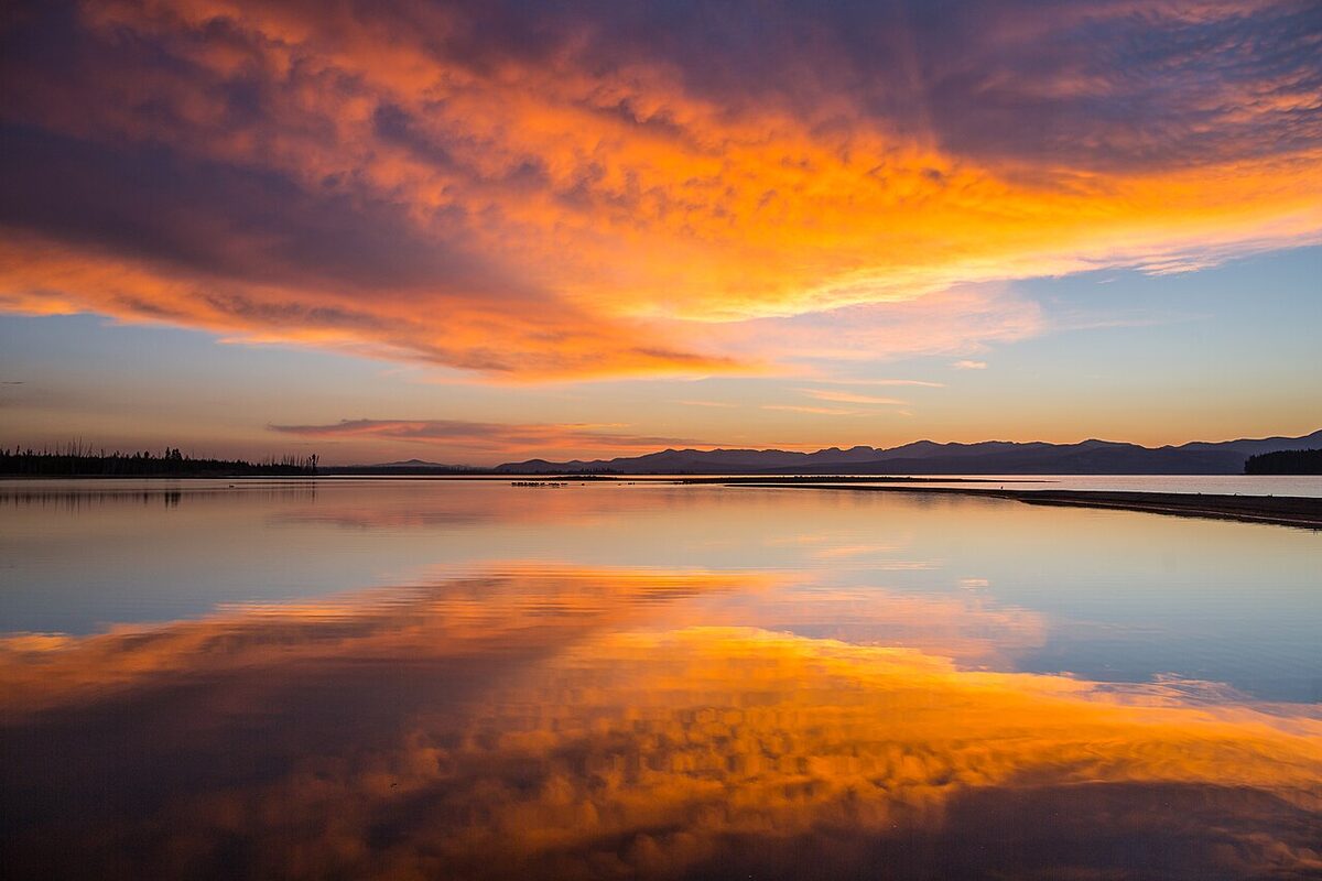 Sunrise reflected across a calm mountain lake